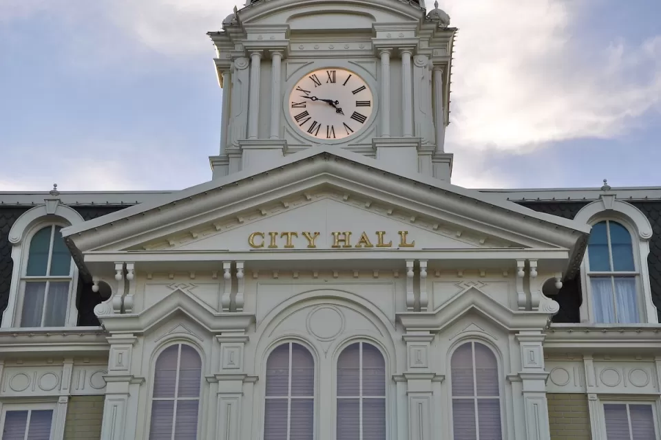 White neoclassical building with cupola and City Hall lettering on front.